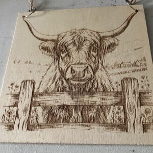 A highland cow on a wood plaque