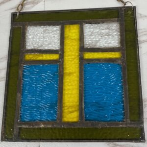 A FRAMED SUNCATCHER  WITH A CROSS ON IT
